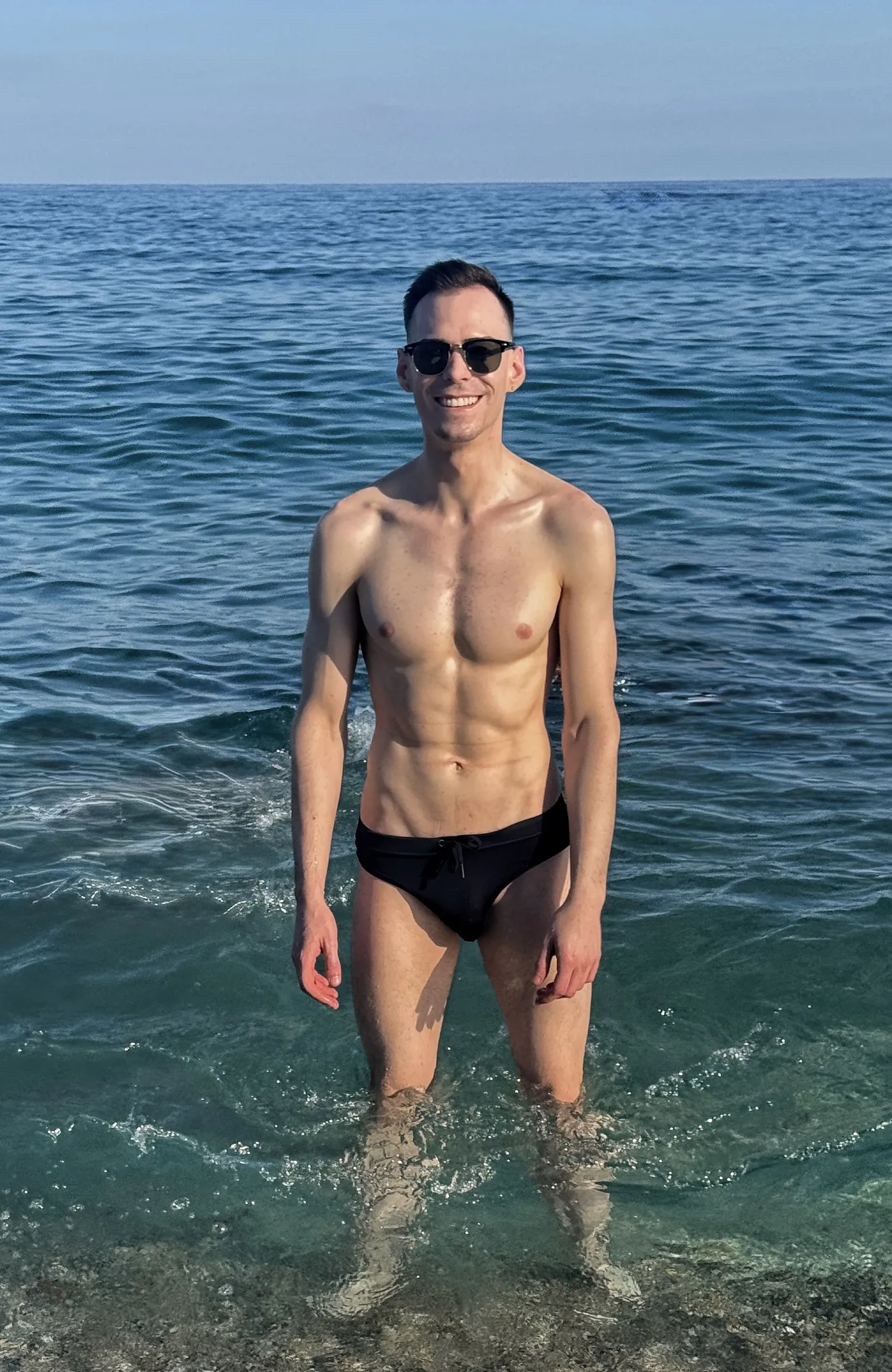István walking through the sea in swimwear, smiling