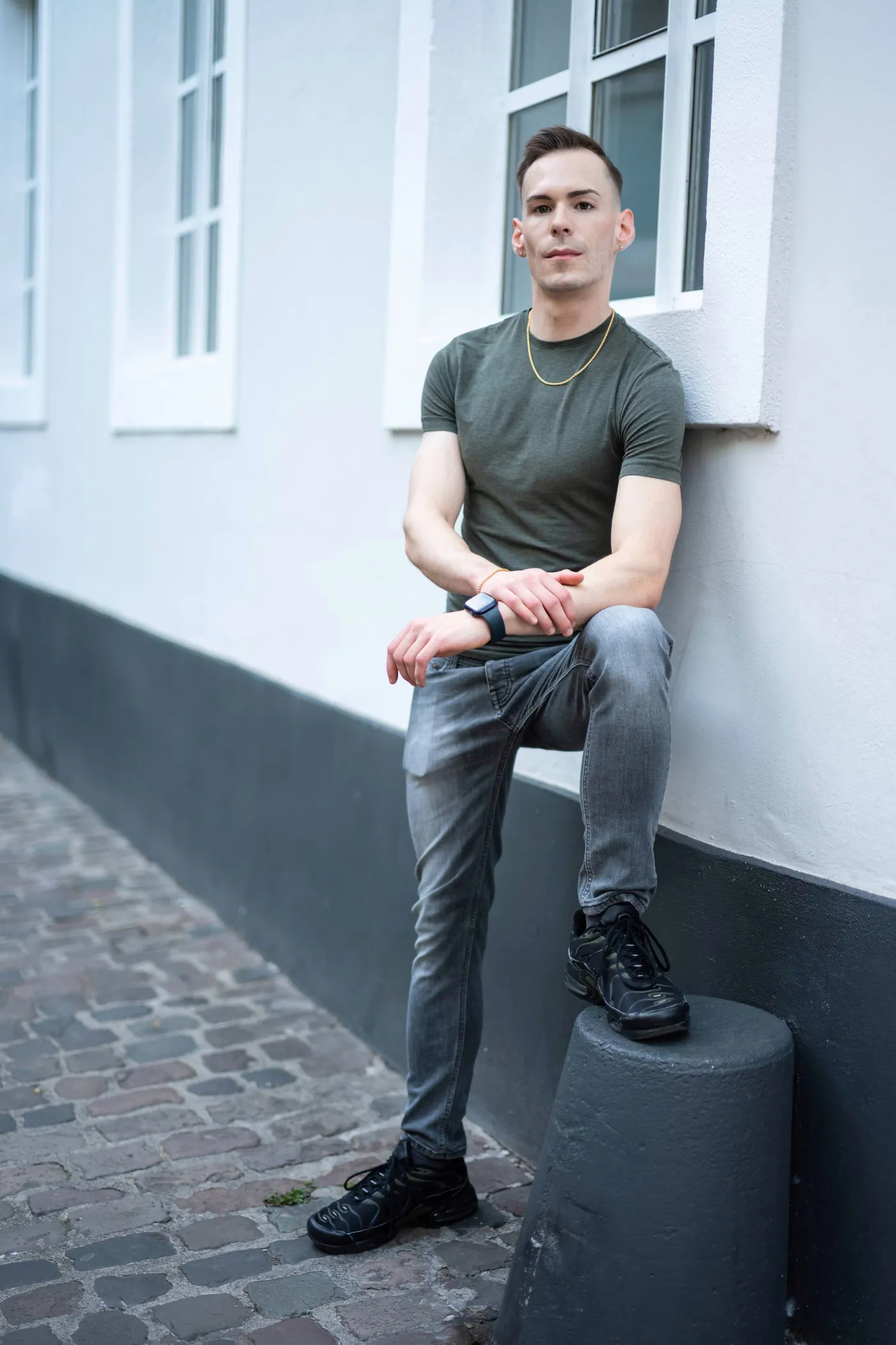 István leaning against a wall on a cobblestone street