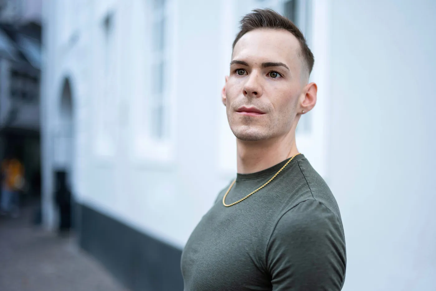 István standing against a white building facade