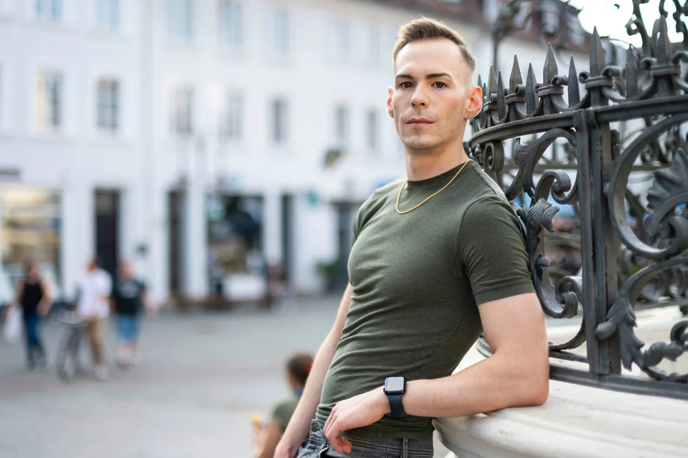 István leaning on a railing in a town square